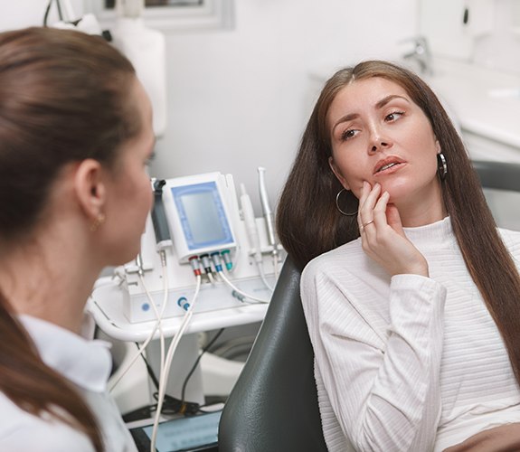 a woman in a dental chair holding her mouth