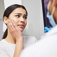 Woman holding cheek and listening to her dentist