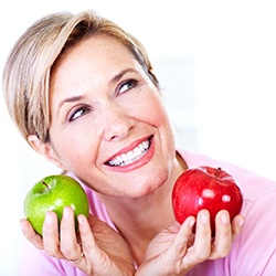 Woman with dental implants enjoying crisp, fresh apples