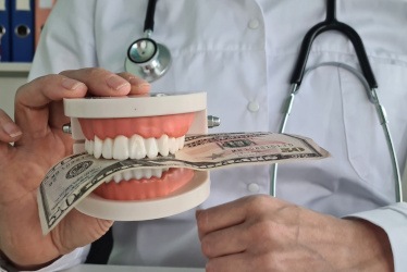 Dentist holding mouth mold with money